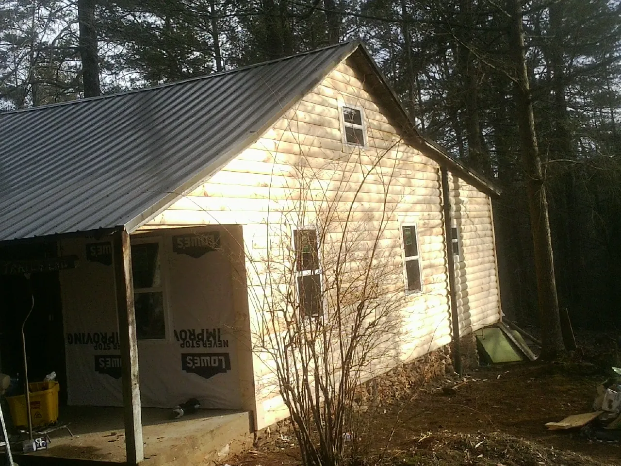 Log siding gable end under a dark metal roof edge in Pearblossom