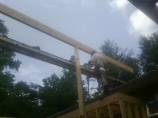 Carpenter setting a ridge beam over a new addition frame — Ice Dam Removal by Roofing Brothers in Pearblossom