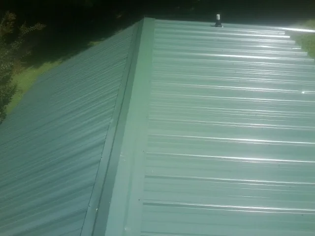 New green metal panels meeting at the ridge of a roof — Flat Roof Repair work by our crew in Pearblossom
