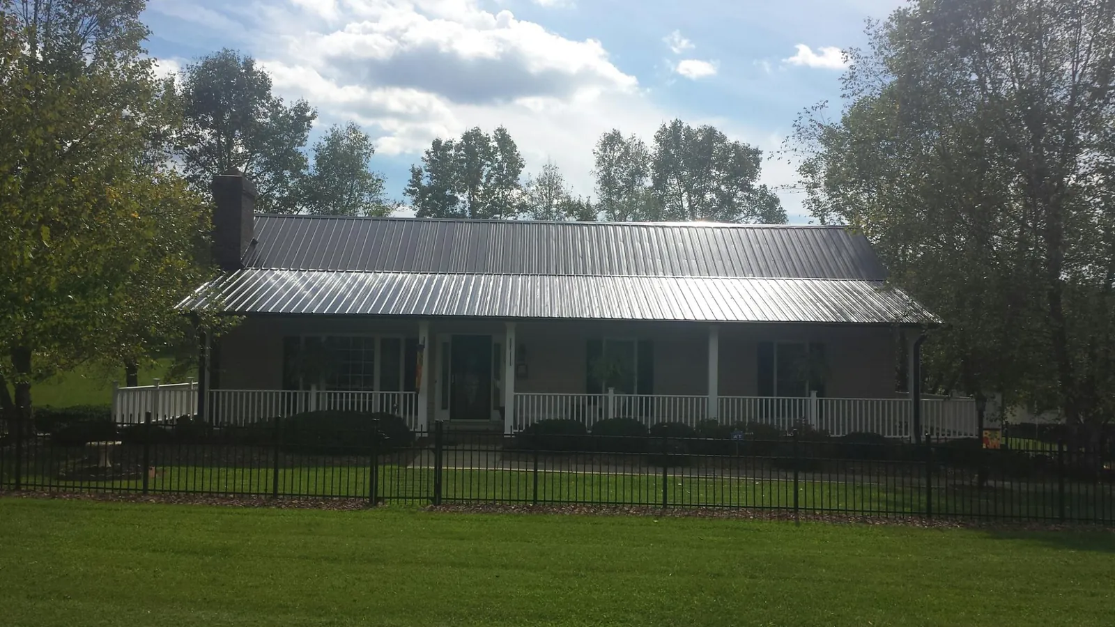 Gray metal roof on a brick ranch with a full width front porch — Gutter Guard Installation work by our crew in Pearblossom