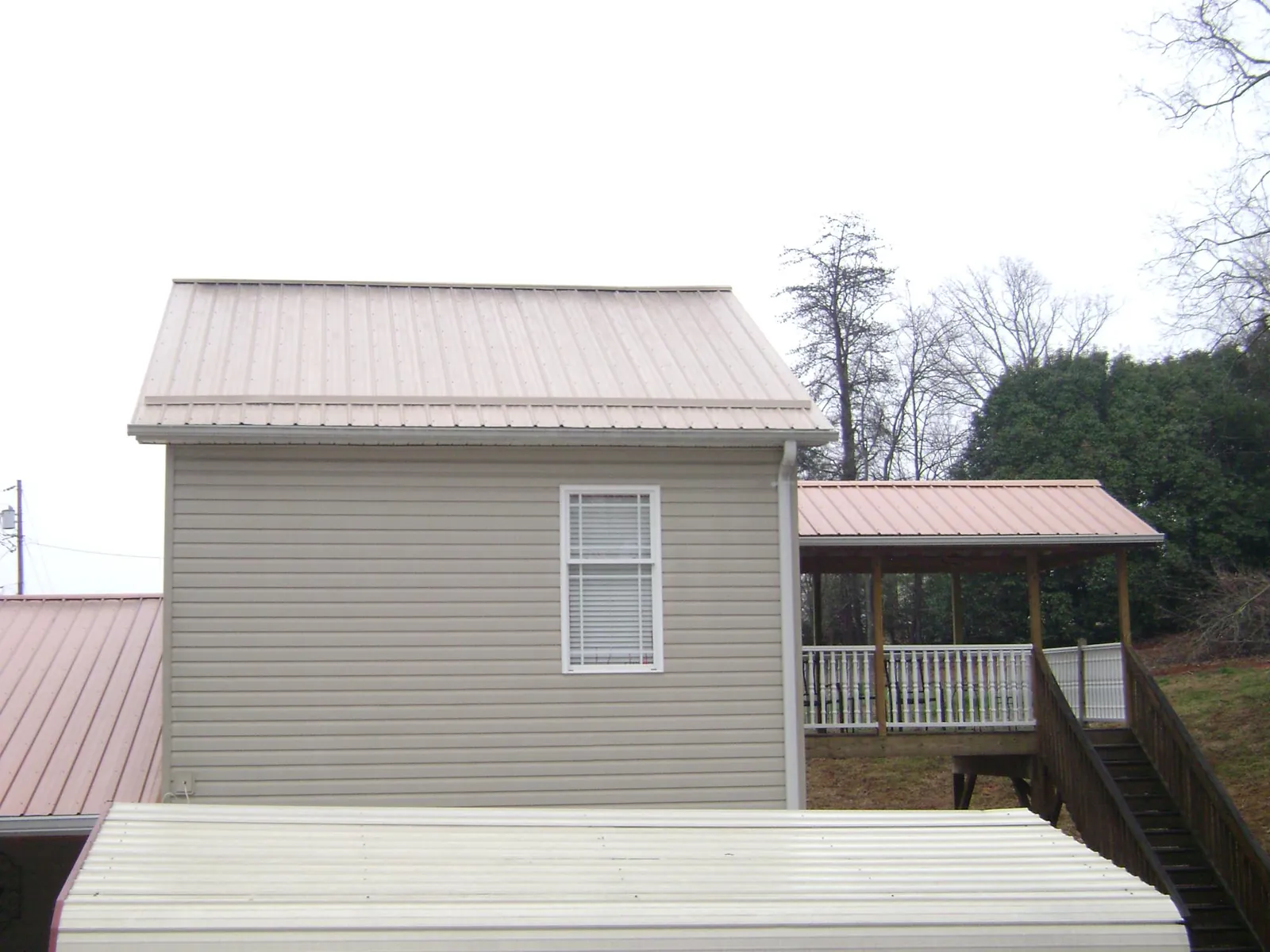 Tan metal roofs on a two story addition and attached porch, from a Roof Replacement job in Pearblossom