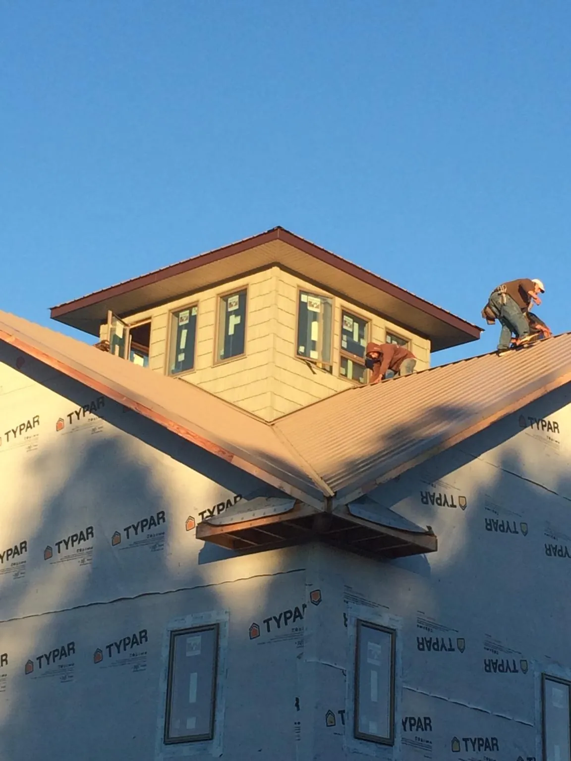 Roofers working around a rooftop cupola on a new metal roof at sunset — Roof Waterproofing in Pearblossom by Roofing Brothers